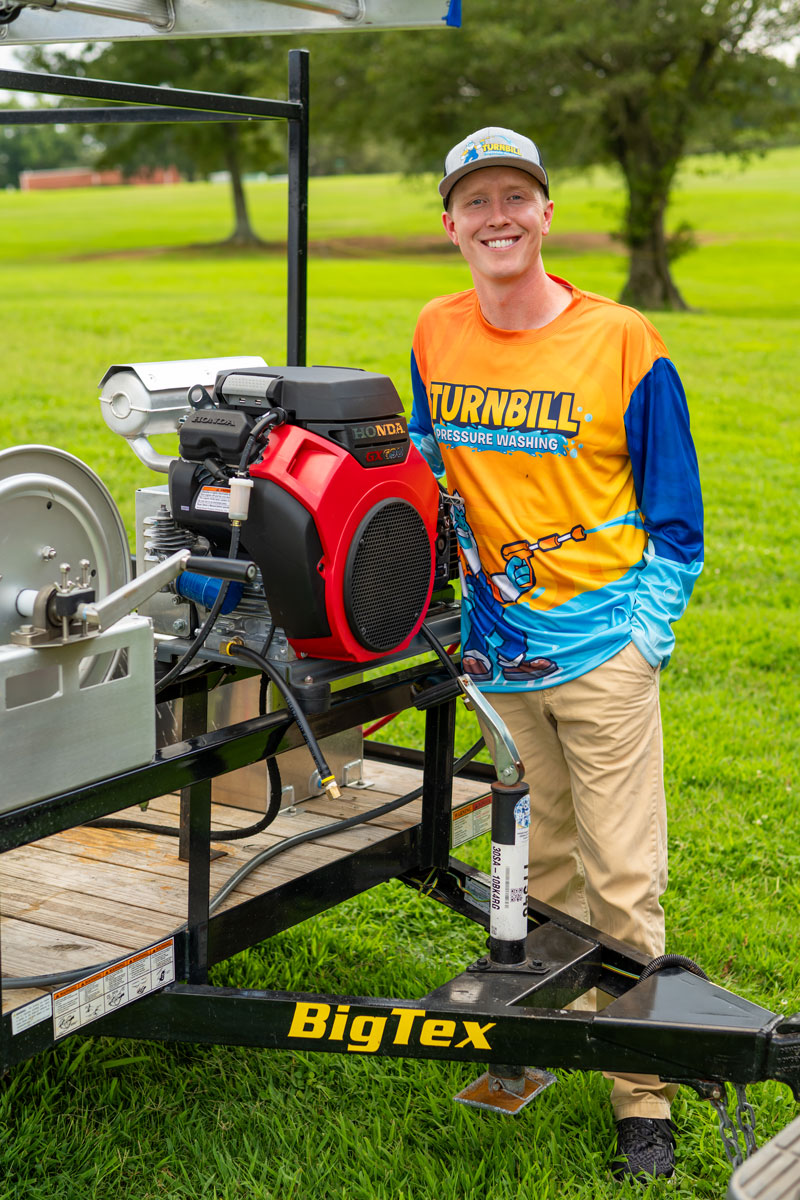 Jacob Turnbill beside trailer hauling pressure washing equipment